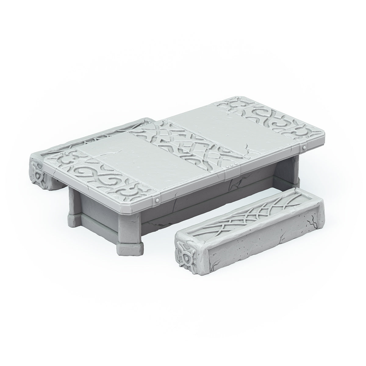 A grey miniature stone table with intricate carvings sits next to a matching stone bench