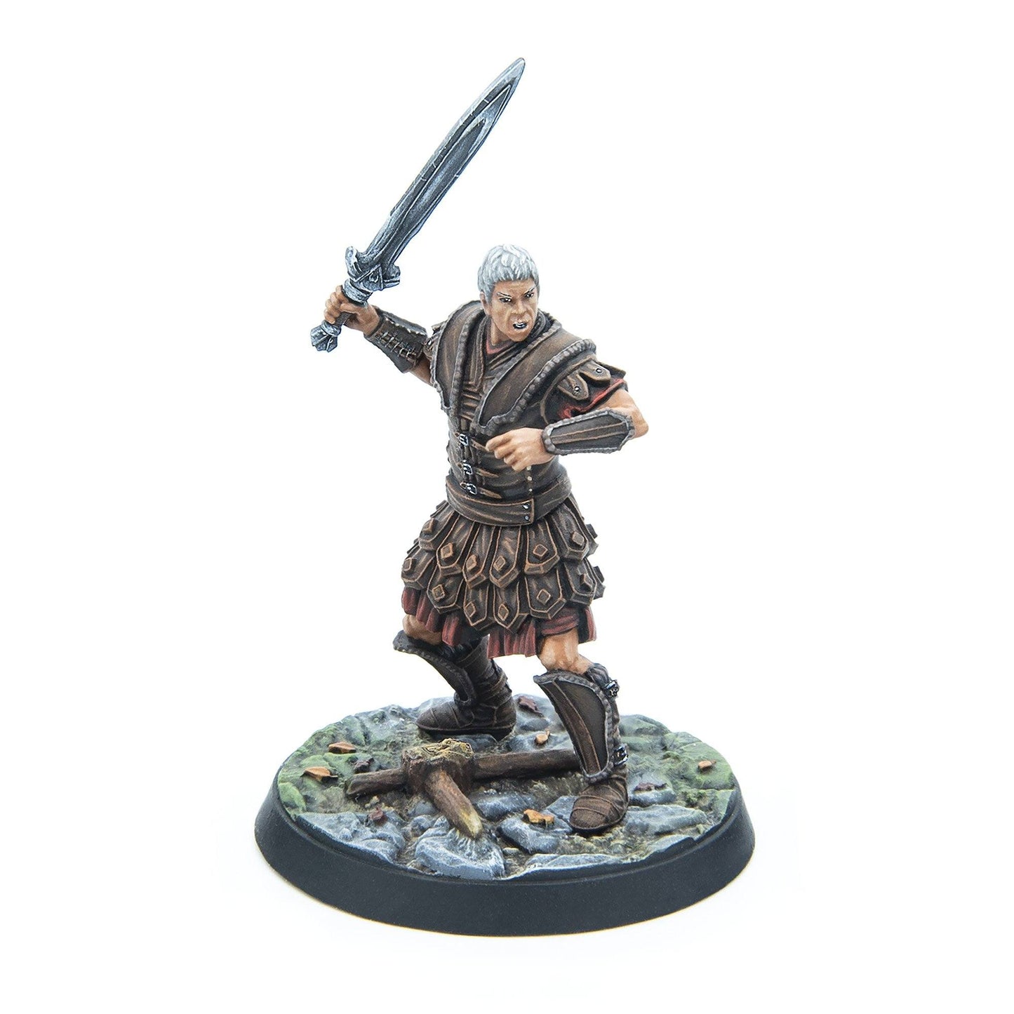 A grey-haired warrior miniature in leather armor fiercely swings a sword, standing on a rocky base