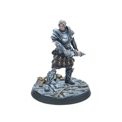 A blonde female warrior miniature in grey plate armor, holding a crossbow, standing on a textured stone base