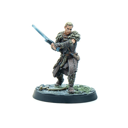 A painted miniature of a male warrior in fur armor brandishing a two-handed sword, standing on a mossy base with bones.