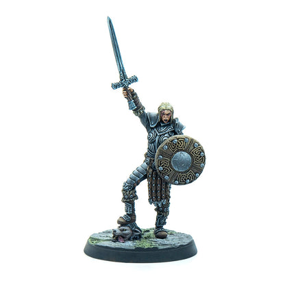 Miniature of a blonde armored female warrior raising a sword, holding a shield, and standing on a severed wolf head.