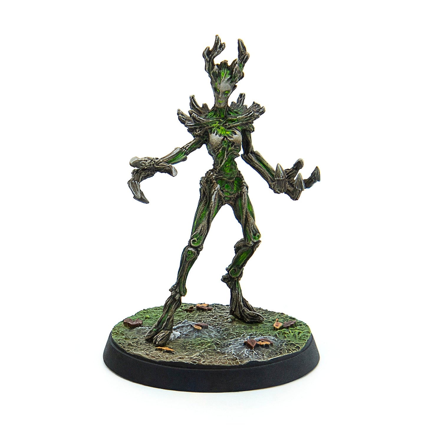 A green and bark-coloured humanoid tree creature miniature, with glowing green accents, standing on a grassy base with fallen leaves