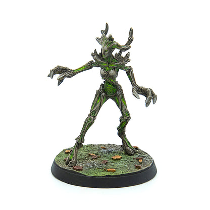 A tree-like fantasy miniature with bark skin, vibrant green highlights, and clawed hands, standing on a textured base