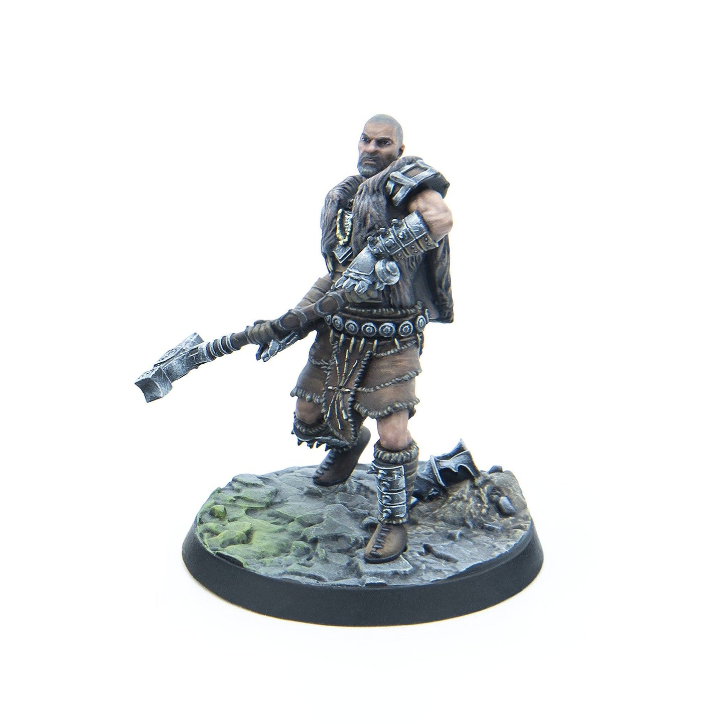 A miniature of a bald, bearded warrior in fur armor, holding a large ornate axe, standing on a rocky base