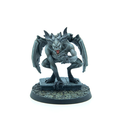Grey gargoyle miniature with large horns, bat wings, bared fangs, and claws, crouching on a stone base