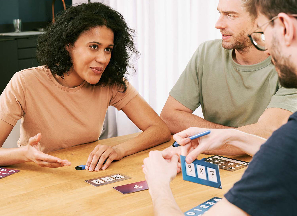 Close-up lifestyle image of hands holding The Number Game cards during an active game session