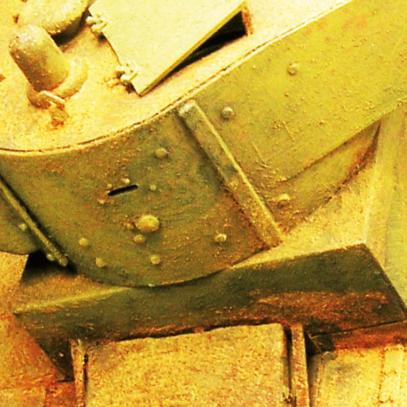 Weathered olive-green tank armor close-up, with heavy riveted plating and a narrow vision slot