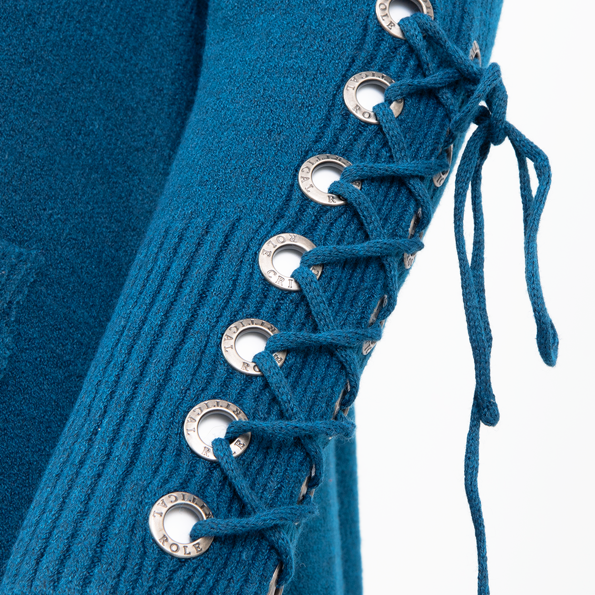 A close-up of blue knitted fabric featuring decorative side lacing: silver "CRITICAL ROLE" eyelets and a matching blue string tied