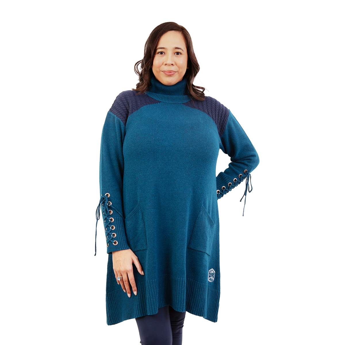 Smiling woman in a teal turtleneck sweater tunic with dark blue textured shoulders, laced sleeve cuffs, and front pockets
