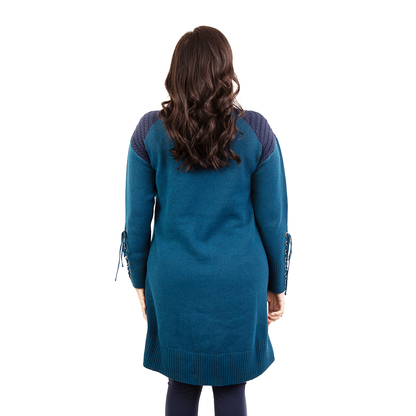 Woman from behind in a long teal tunic with textured navy shoulders and lace-up cuffs