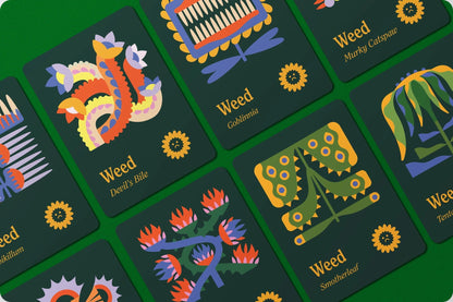 Dark green game cards with colorful, stylized 'weed' illustrations, names, and sad sunflower icons, spread on a green surface