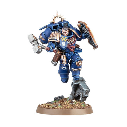 Blue armored miniature figure of a Space Marine charging, holding a shield and power hammer