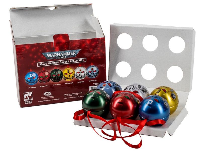 An open box displaying six colourful Warhammer 40K Space Marines helmet-shaped baubles with red ribbons