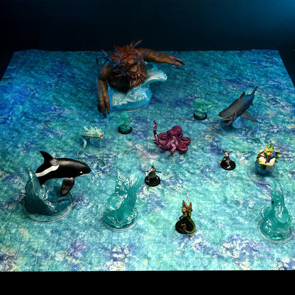 Game miniatures on a blue game mat: A massive brown sea monster, an orca, a shark, an octopus, and several small adventurers