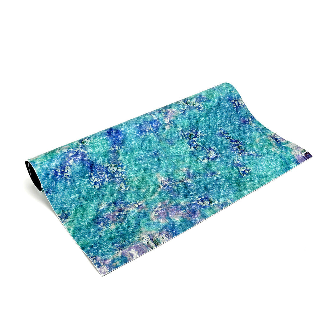 A partially unrolled roll of vibrant blue, green, and purple patterned material with a mottled, grid texture