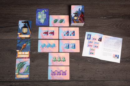 A detailed tabletop shot of the Isle of Night game setup showing cards, tokens, and miniatures arranged on a textured game board with players’ hands in action