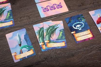 A photo showing a player holding cards while playing Isle of Night, with the game board and pieces visible in the background