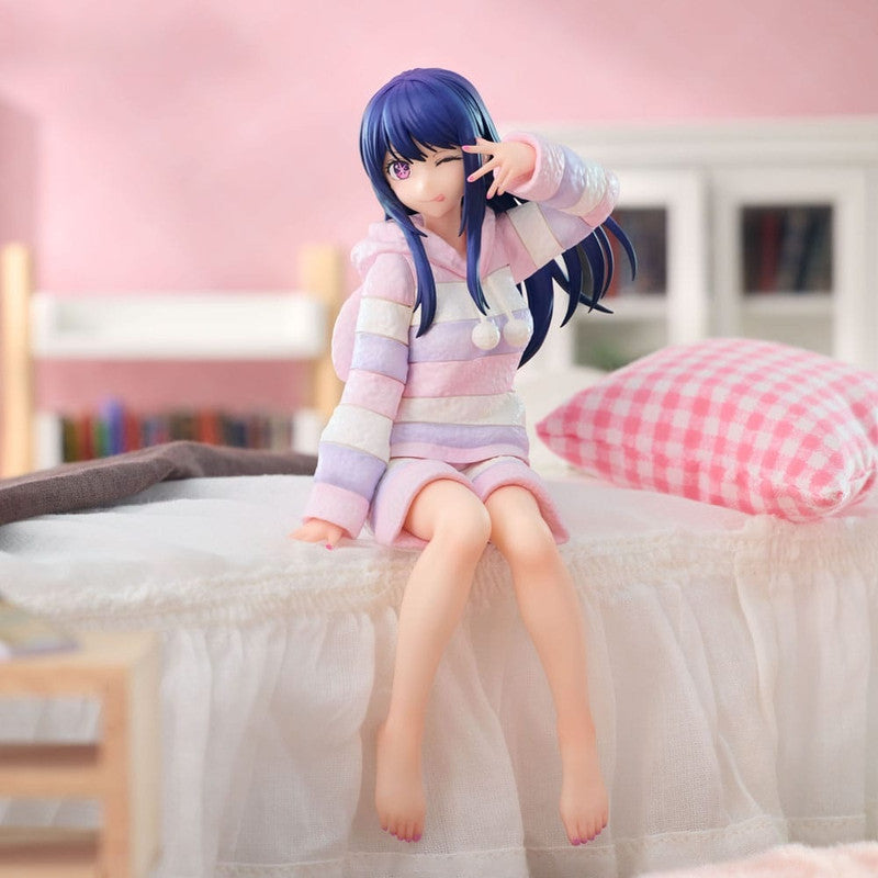 Anime girl figure in pastel striped pajamas sitting on a bed winking and making a peace sign