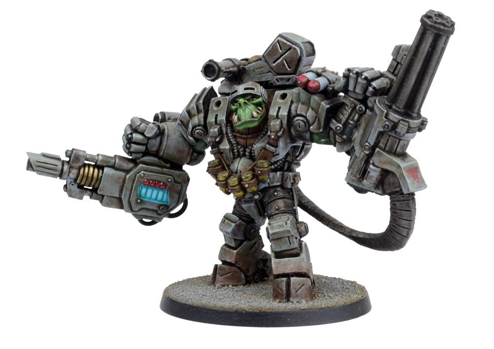 A formidable green-skinned Ork miniature in gray power armor, wielding a massive cannon, gatling gun, and shoulder missiles