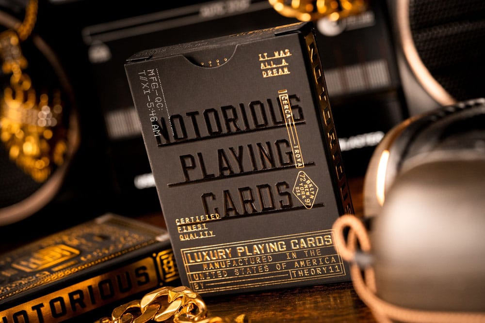 Close-up of a black and gold Notorious Playing Cards deck box, framed by a thick gold chain
