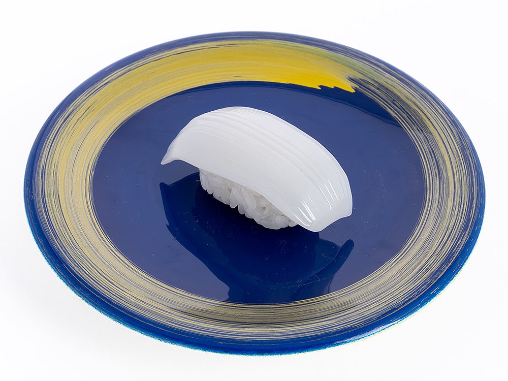 White squid nigiri sushi on a blue plate with yellow brushstroke patterns