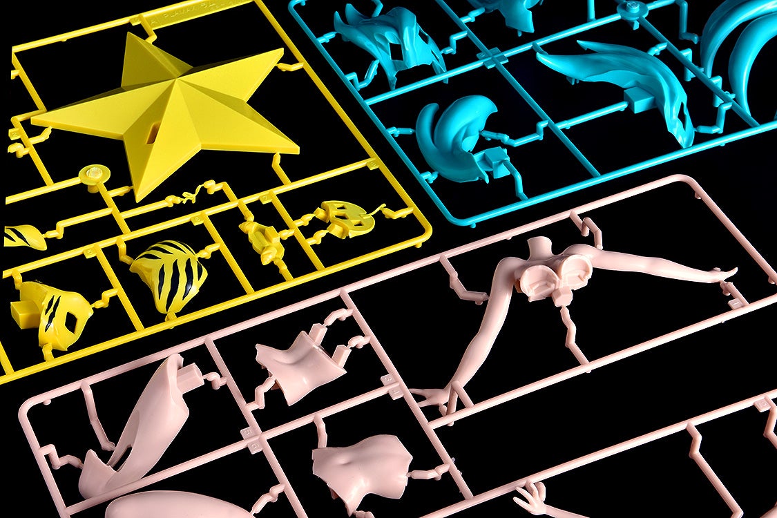 Unassembled plastic model kit pieces in yellow blue and pink on a black background