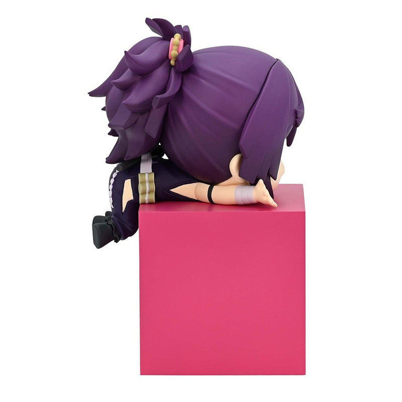 Purple anime figure with dark clothing and gold accents sitting on a pink block